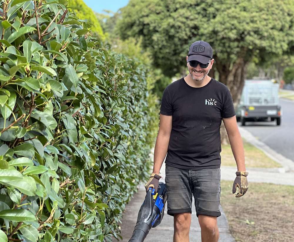 Male landscaper with leaf blower, on suburban street