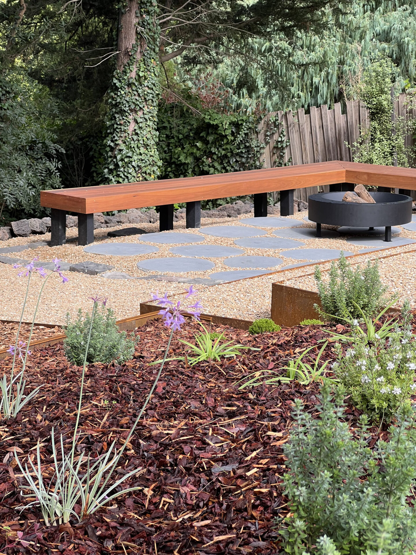 Outdoor fire with stacks of firewood, on plant filled deck